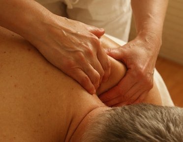 Fisioterapista effettua massaggio al trapezio a paziente disteso su lettino