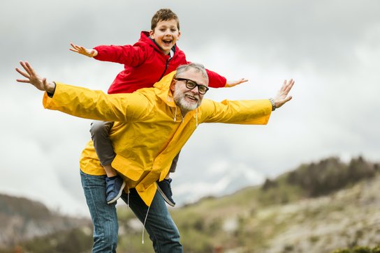 Padre con figlio a cavalcioni sulle spalle, sorridenti trasmettono benessere fisico, come dopo un ciclo di fisioterapia